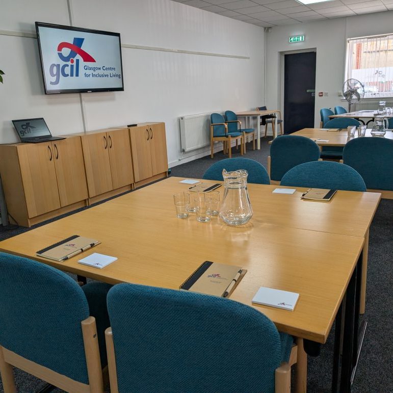 Tables laid out in a conference room with water jugs and glasses in the middle of each table.
