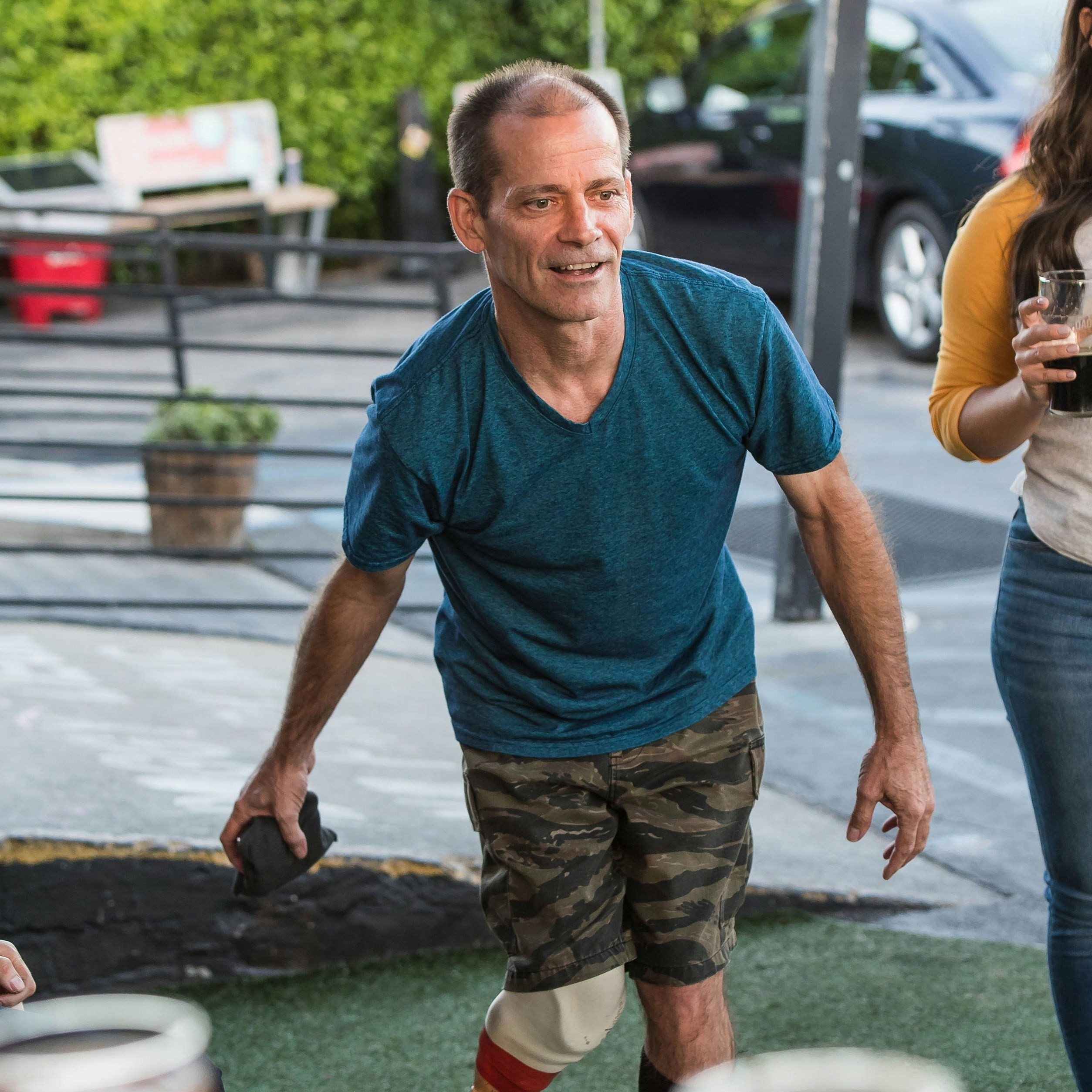 A man with a prosthetic leg is playing a game in a pub.