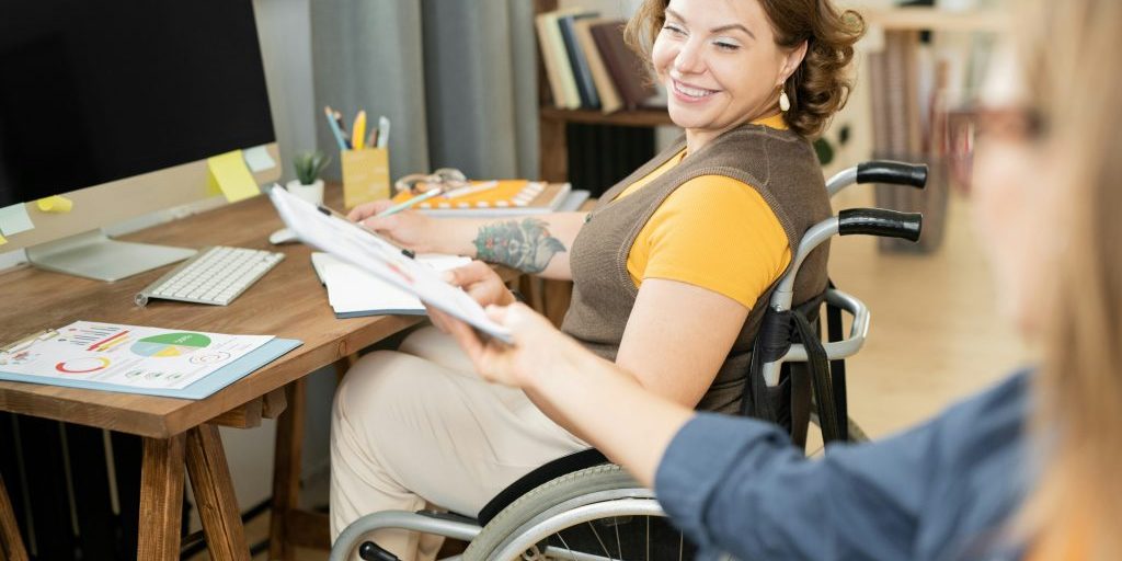 Woman in a wheel chair working on computer and smiling.