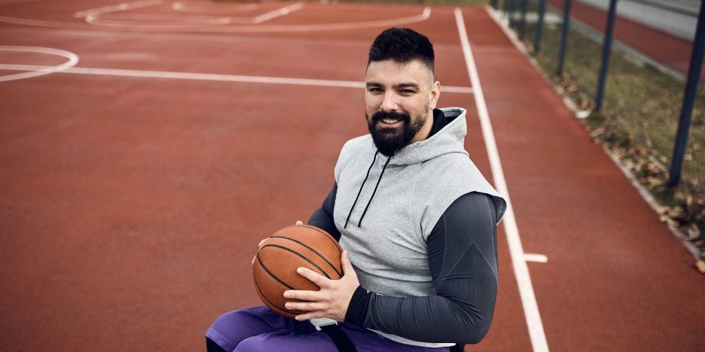 Man in a wheelchair on a basketball court holding a basketball