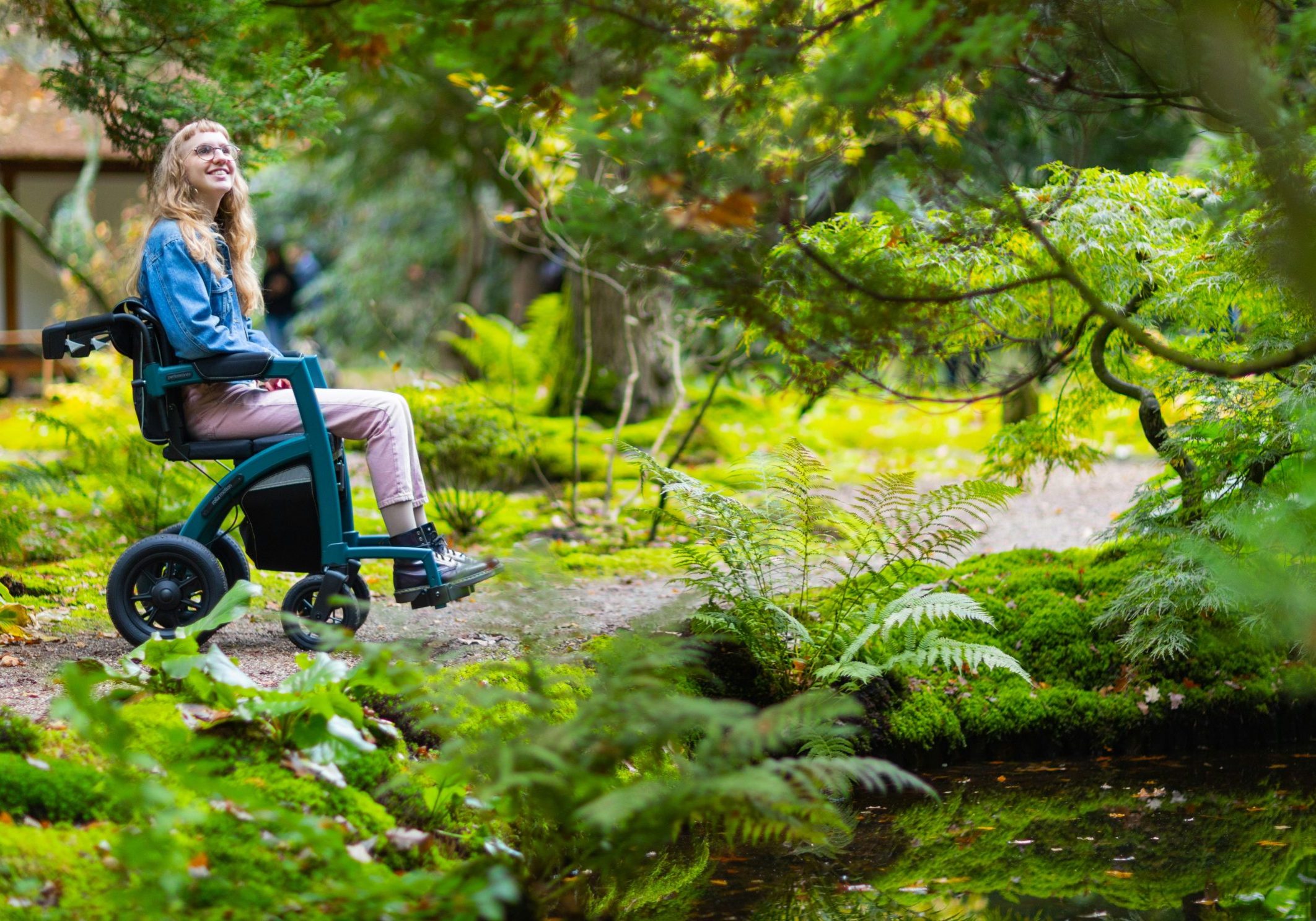 A person with long hair is in a wheelchair in a forrest